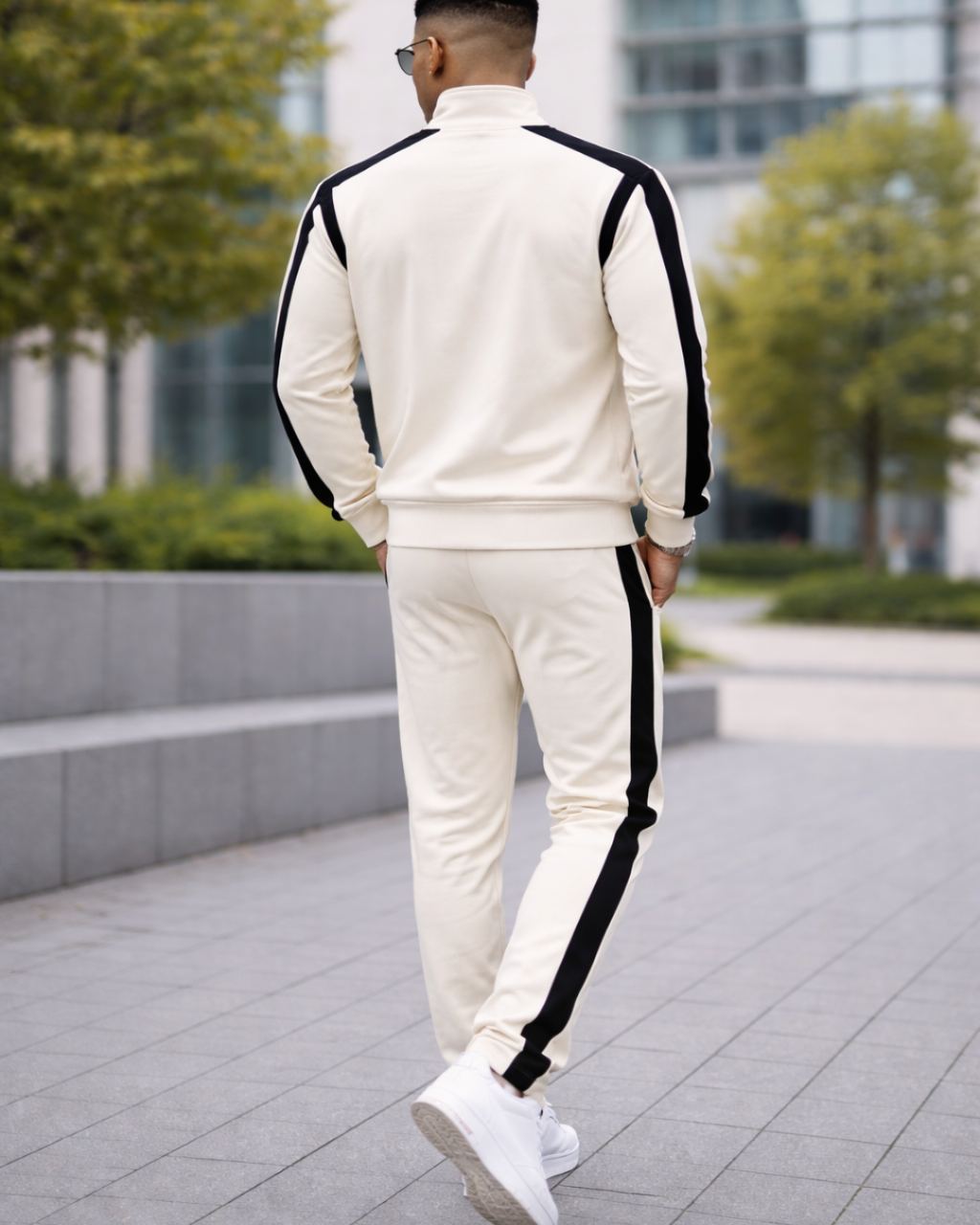 Person wearing a white tracksuit with black stripes walking outdoors.