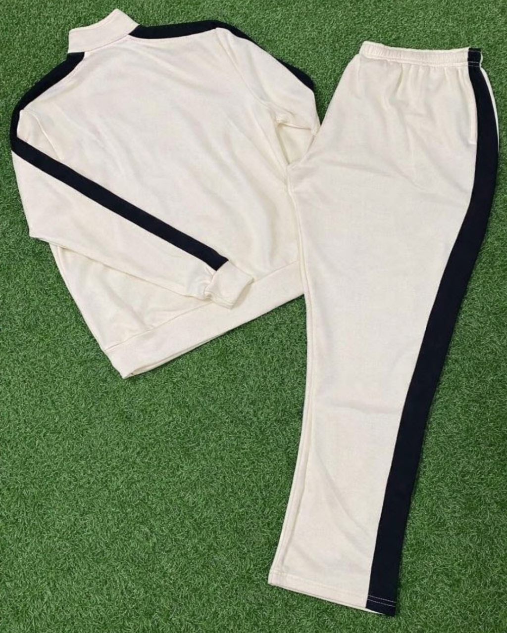 White tracksuit with black stripes on a green grass background