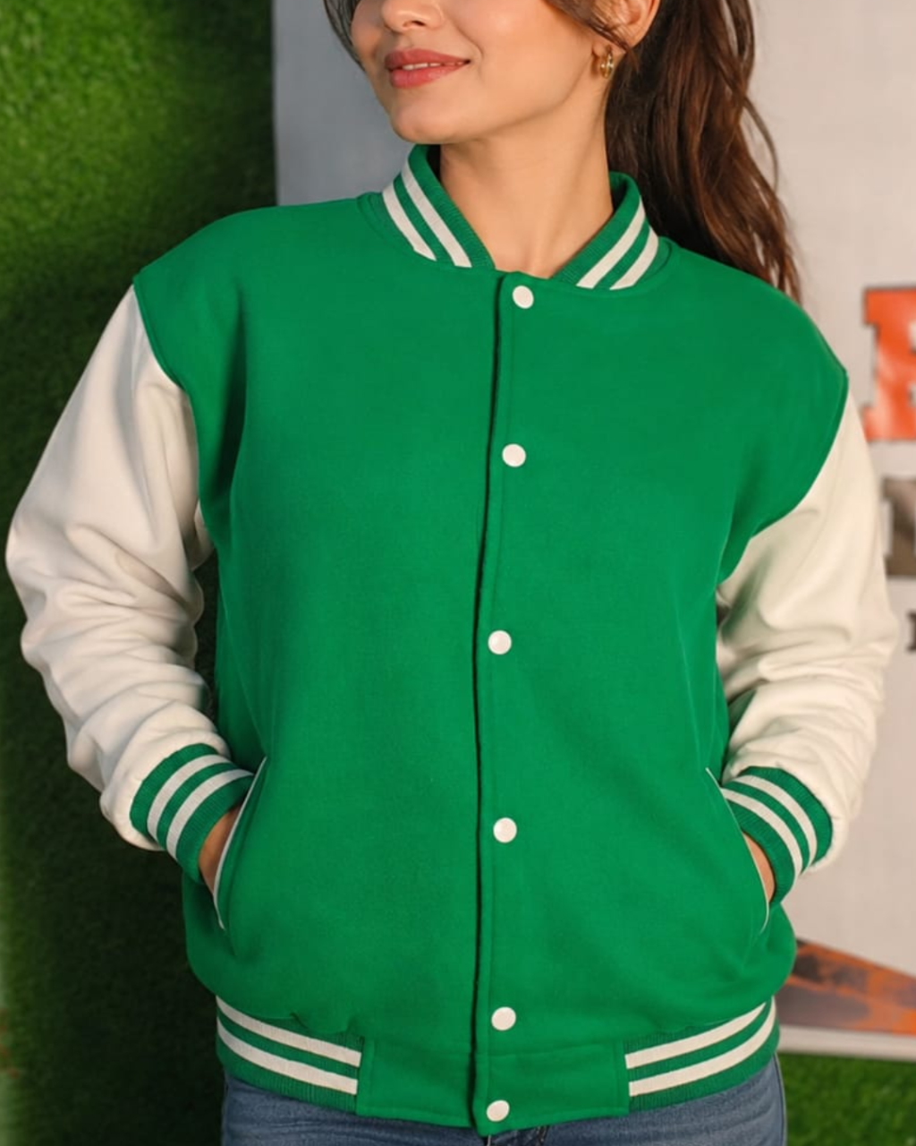 Person wearing a green and white varsity jacket with a blurred background