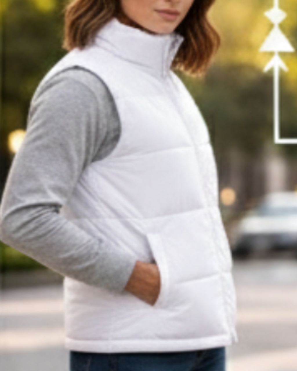 Person wearing a white puffer vest over a gray shirt outdoors.