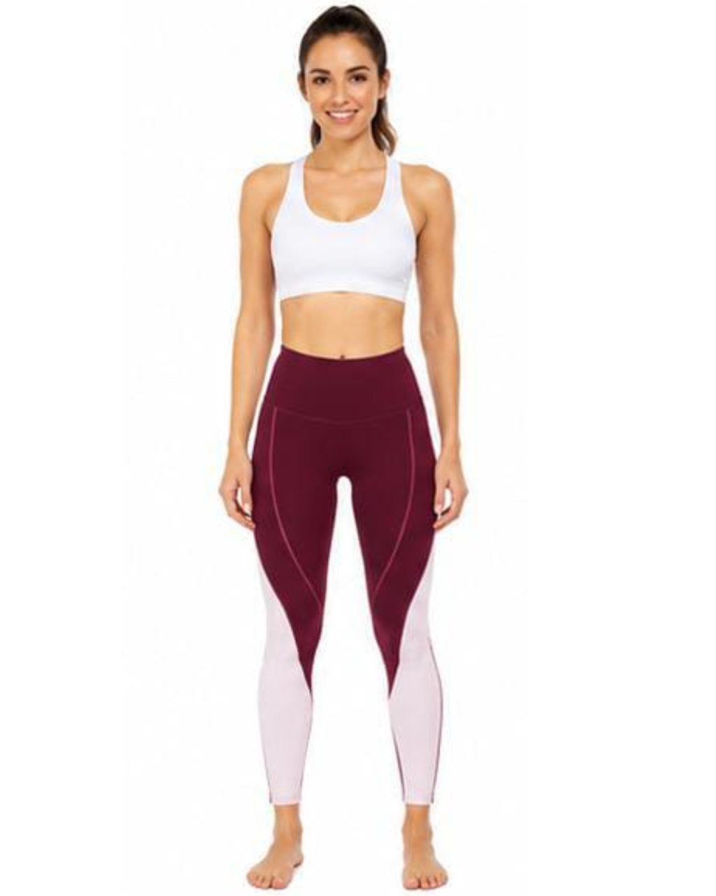A woman modeling high-waisted athletic leggings in burgundy and pale pink, paired with a white sports bra, against a plain white background.