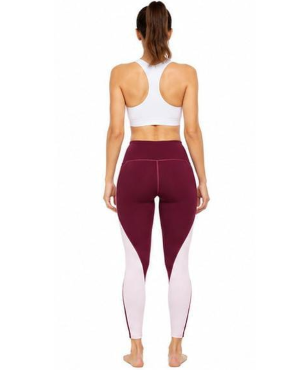 Rear view of a woman wearing colorblock leggings in burgundy and white, paired with a white sports bra, against a plain white background.