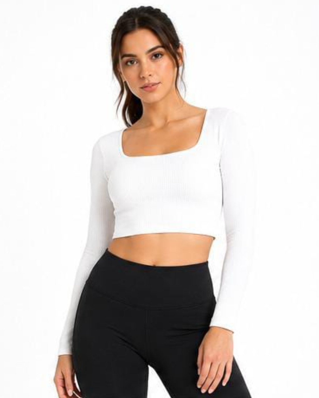 A woman modeling a white long-sleeve ribbed crop top with a square neckline, paired with black leggings, against a plain white background.