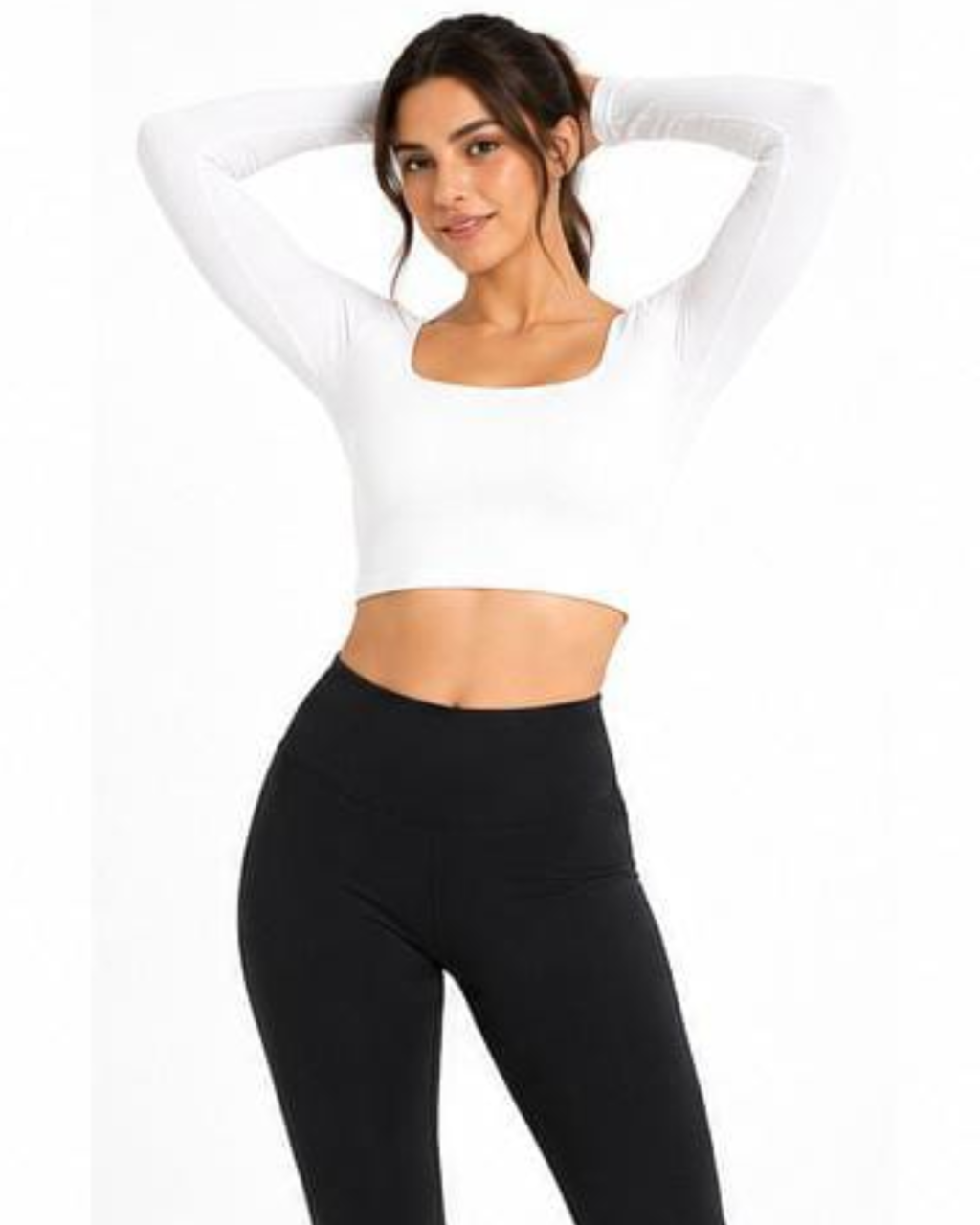 A woman modeling a white long-sleeve crop top with a square neckline and black high-waisted leggings against a plain white background.