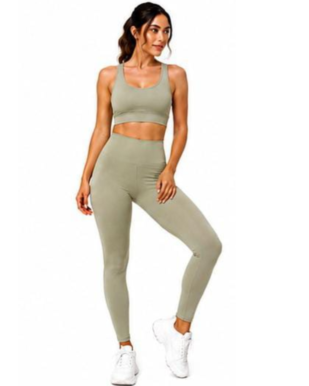 A woman modeling a matching two-piece activewear set consisting of an olive green sports bra and high-waisted leggings, paired with white sneakers, against a plain white background.