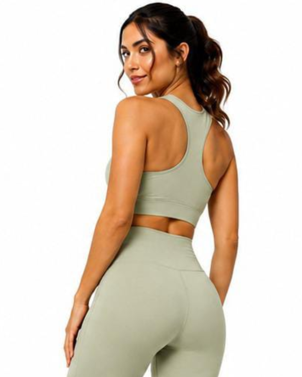 A woman wearing a matching sage green athletic set, featuring a sports bra and high-waisted leggings, shown from a rear three-quarter angle against a plain white background.
