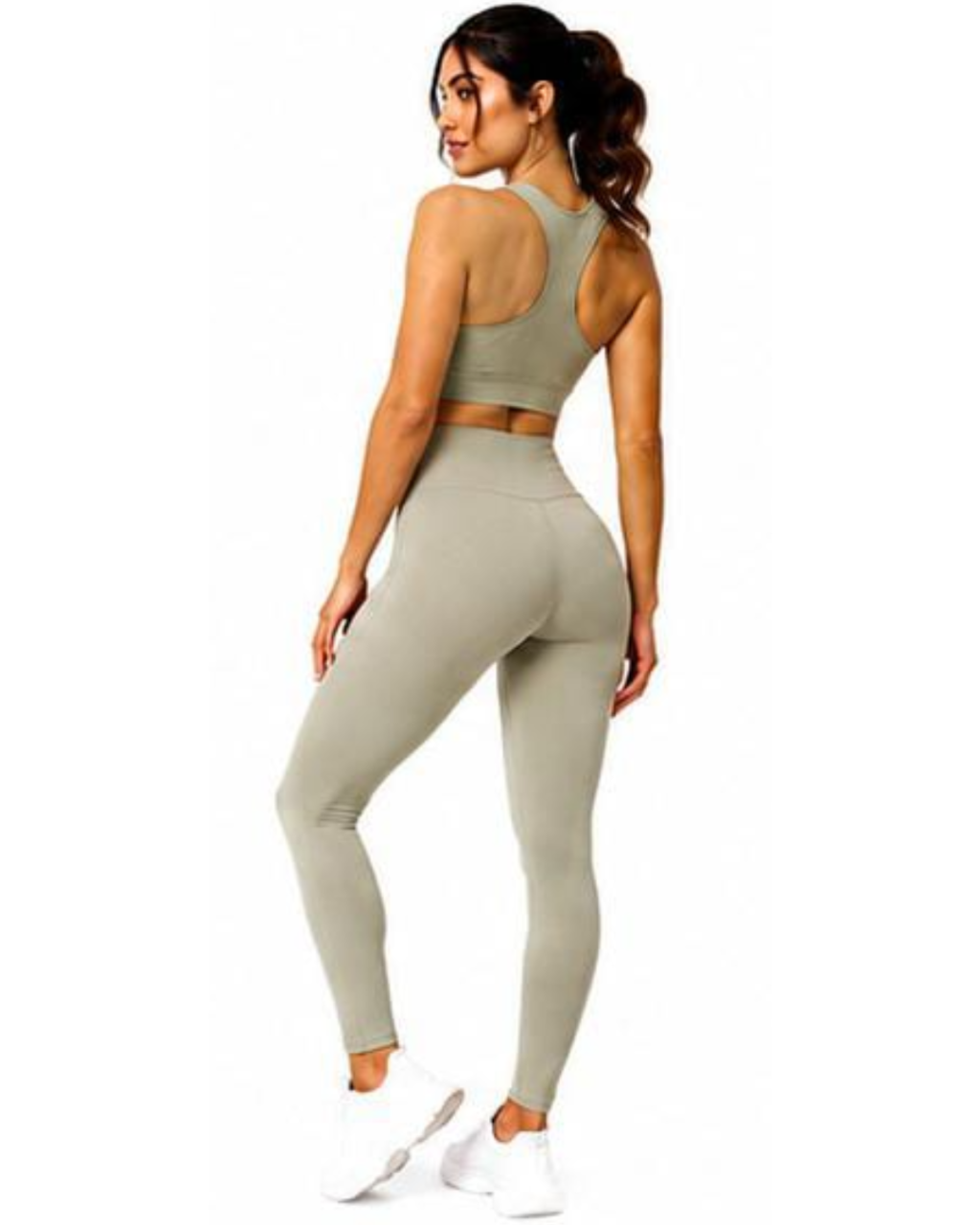 A woman modeling a matching two-piece activewear set consisting of a sports bra and high-waisted leggings in a light sage green color, shown from a rear three-quarter angle against a plain white background.
