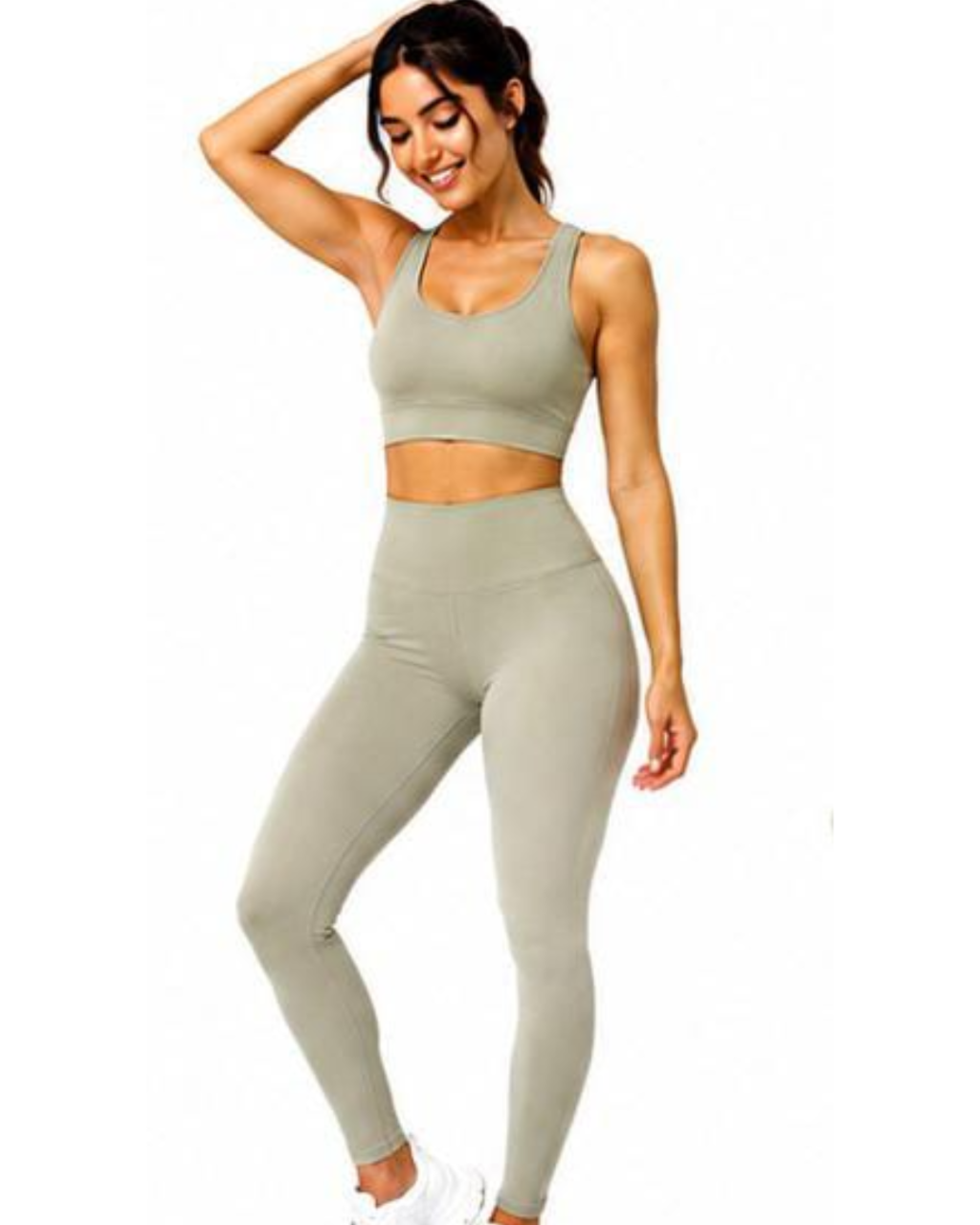 A woman modeling a matching athletic set consisting of a scoop-neck sports bra and high-waisted leggings in a light sage green color, set against a plain white background.