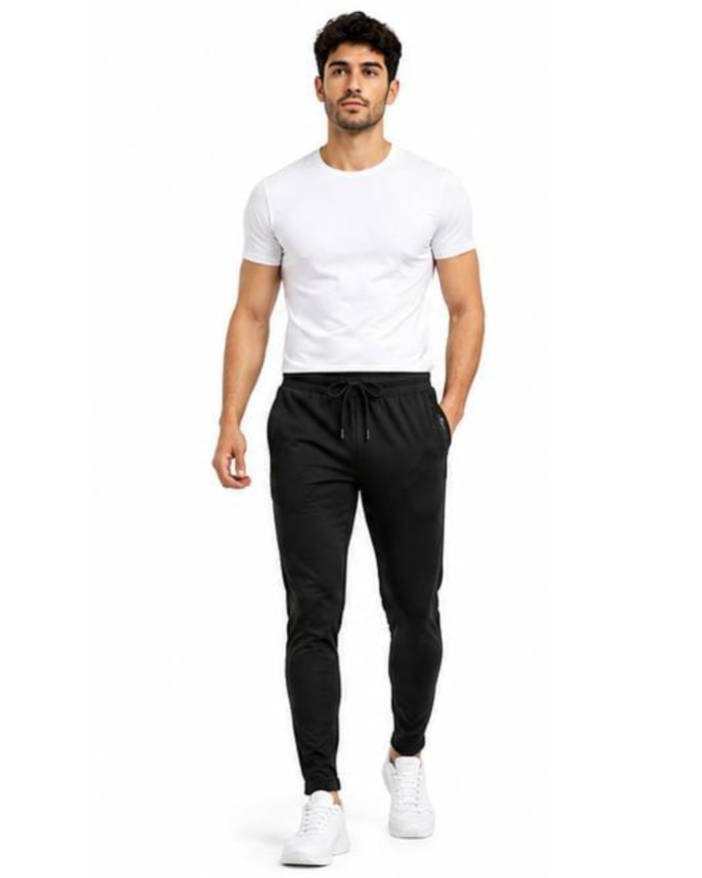 A man modeling black jogger pants with a drawstring waist, paired with a white t-shirt and white sneakers, against a plain white background.
