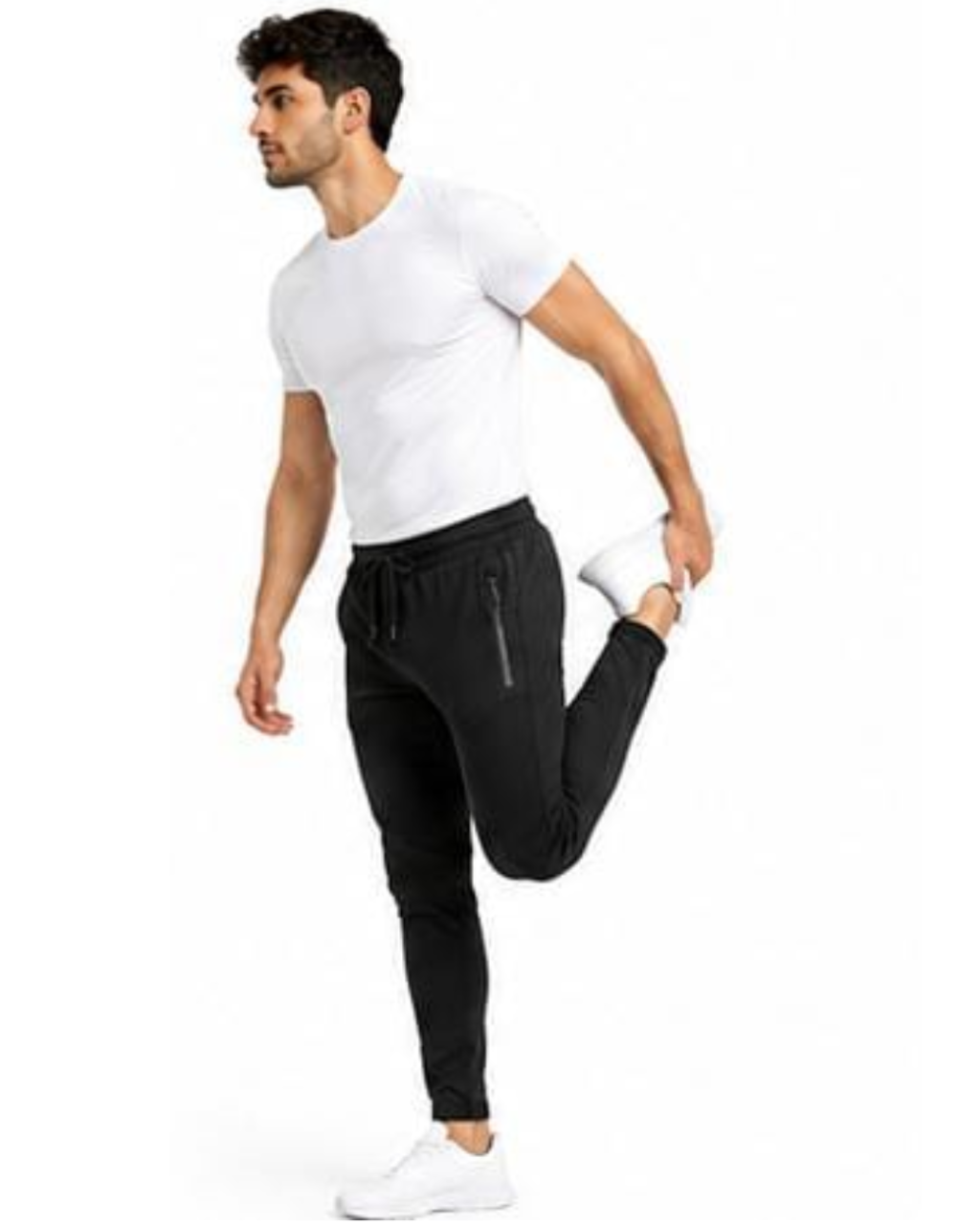A man wearing a white t-shirt and black jogger pants with white sneakers is stretching his leg against a plain white background.