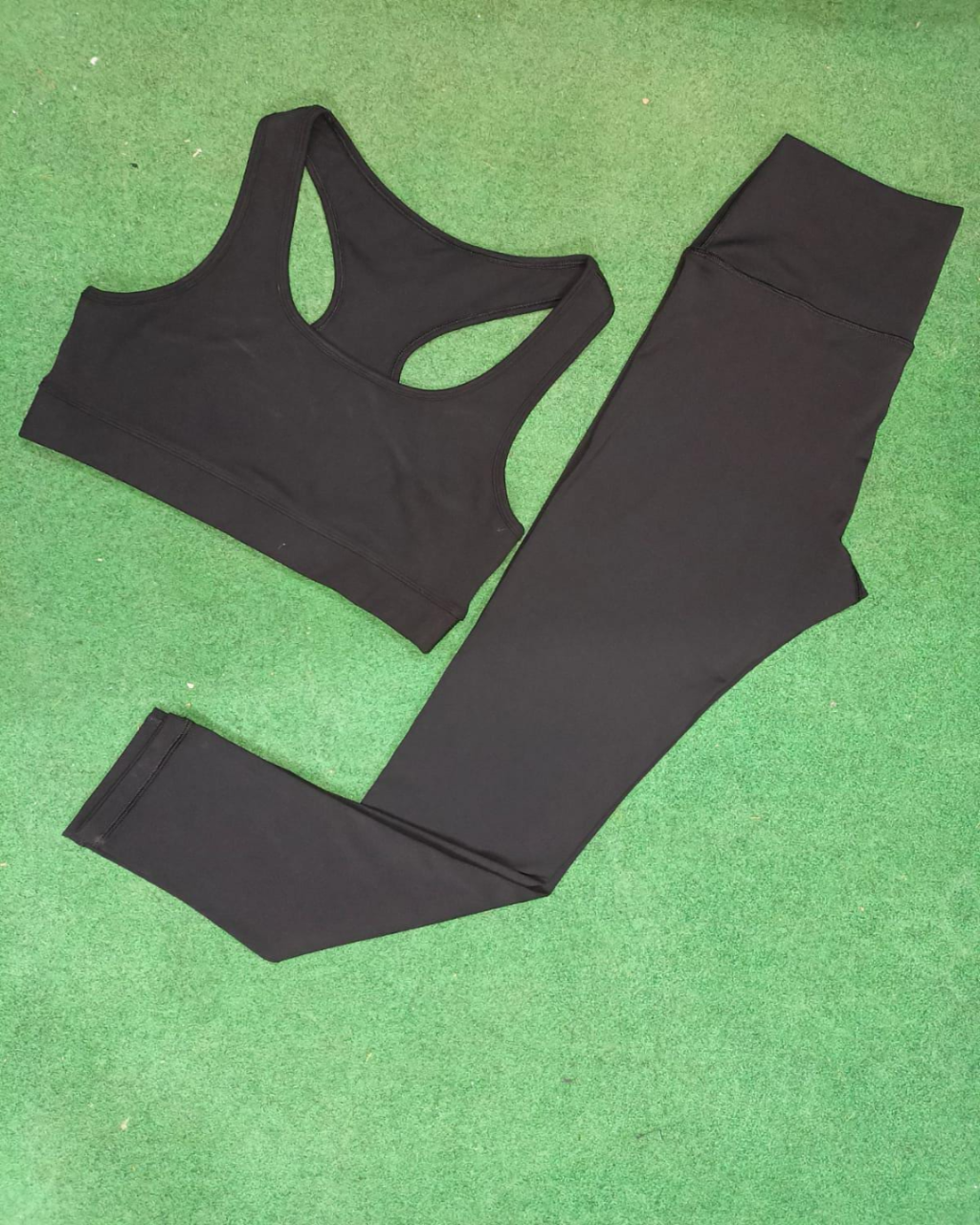 Black sports bra and leggings set on a green surface