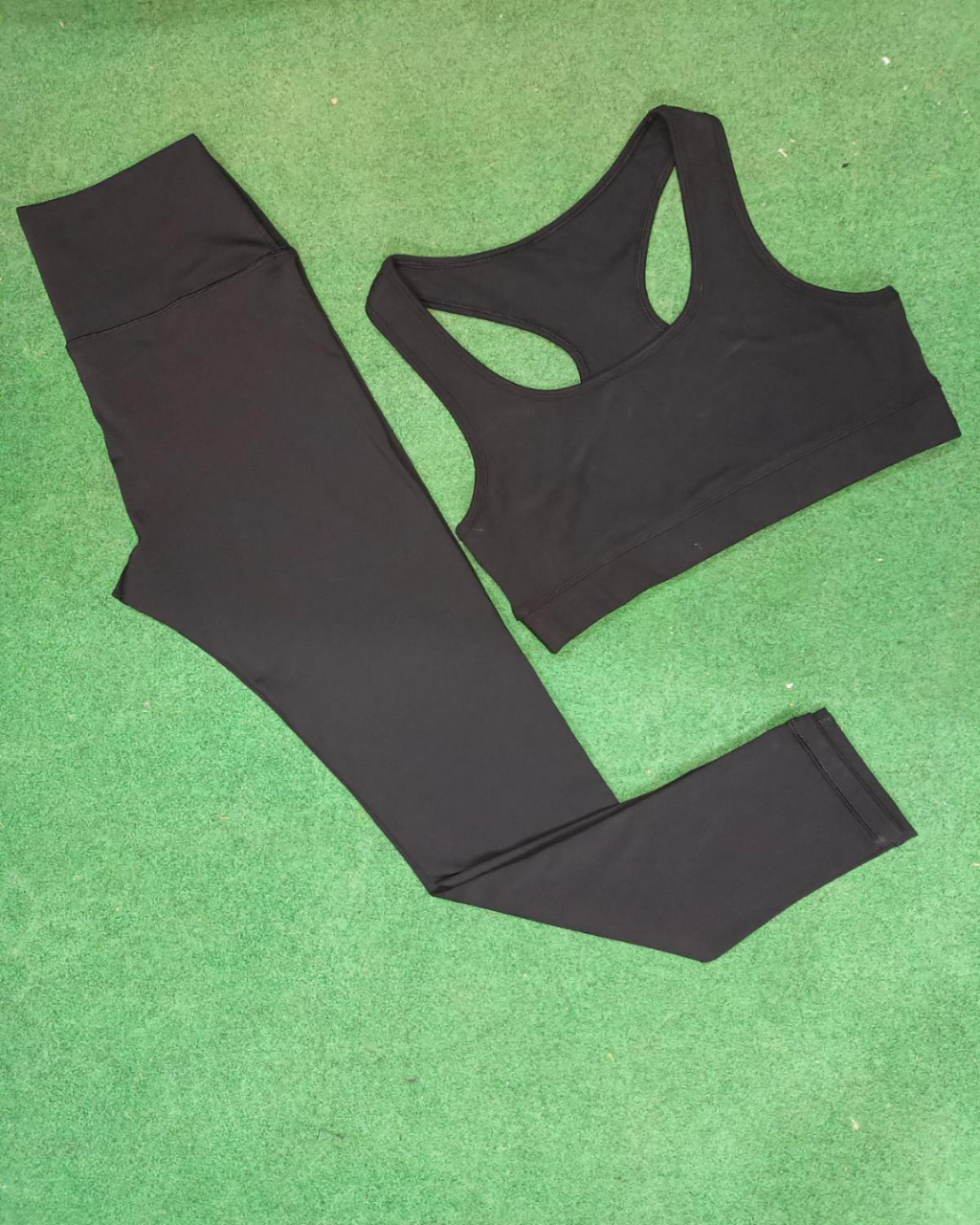 Black sports bra and leggings set on a green surface