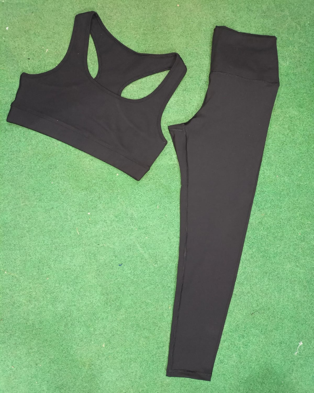 Black sports bra and leggings on a green surface