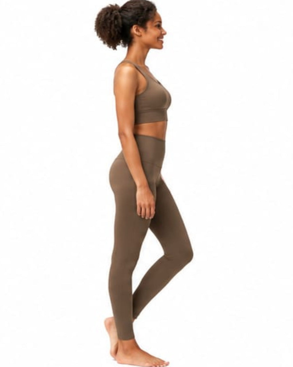 Woman wearing a brown sports bra and leggings on a white background