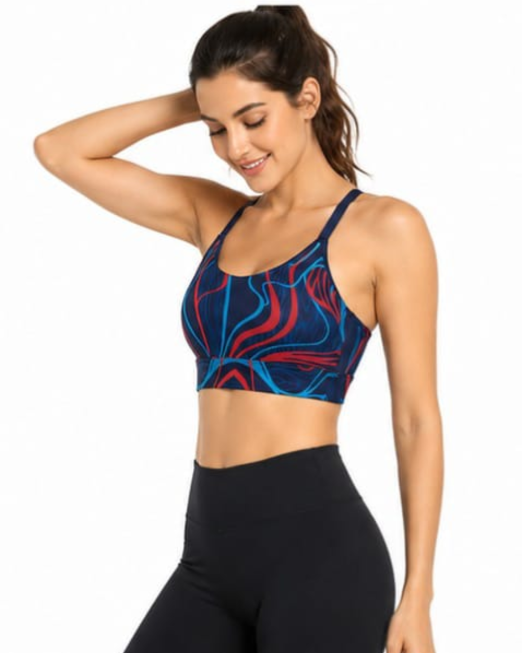 A woman modeling a sports bra with a blue, red, and black abstract swirl pattern, paired with black high-waisted leggings, against a plain white background.