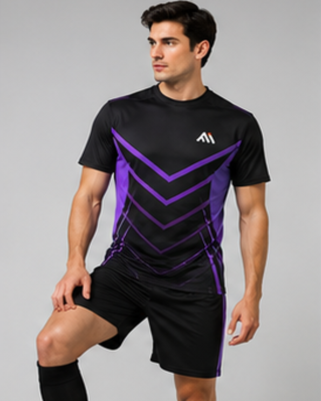 A man modeling a black athletic t-shirt and matching black shorts with purple geometric patterns and a white logo on the chest, set against a plain gray studio background.