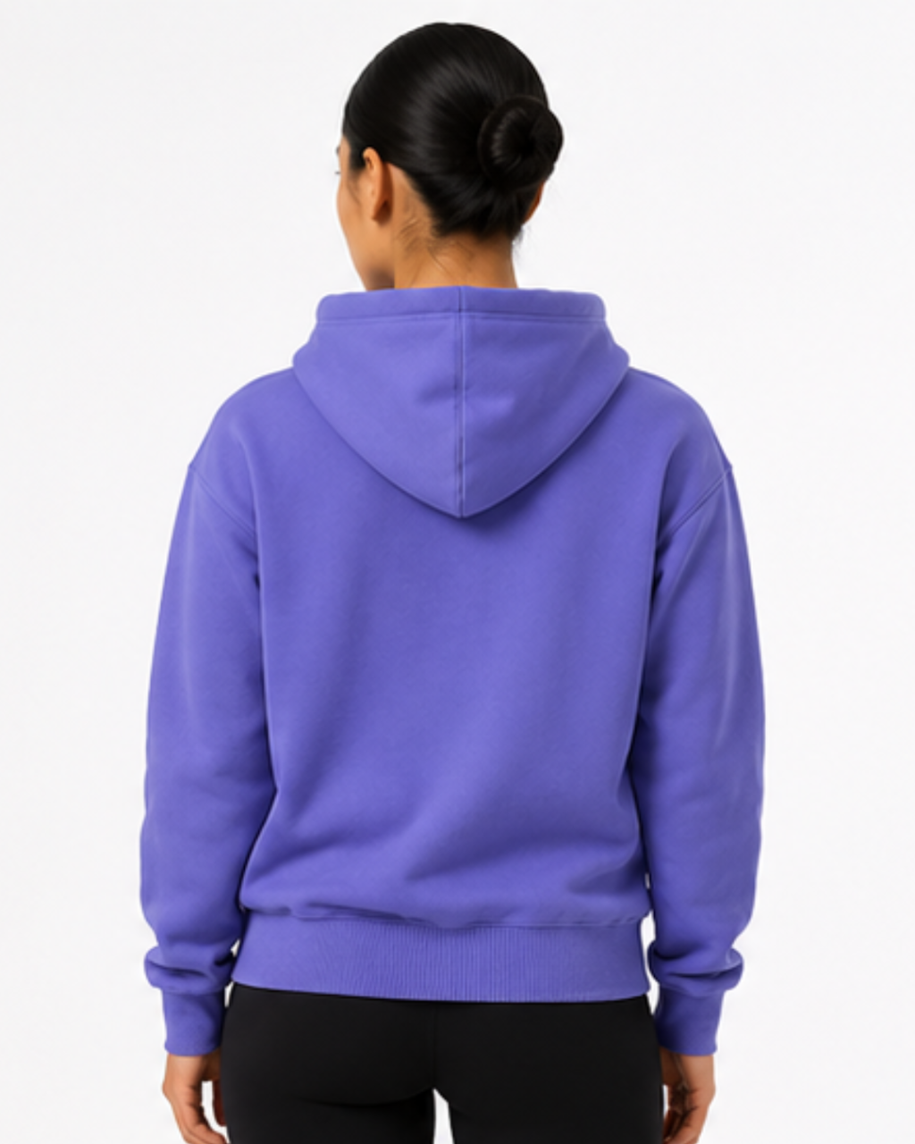 A person shown from the back wearing a solid purple pullover hoodie and black pants against a plain white studio background.