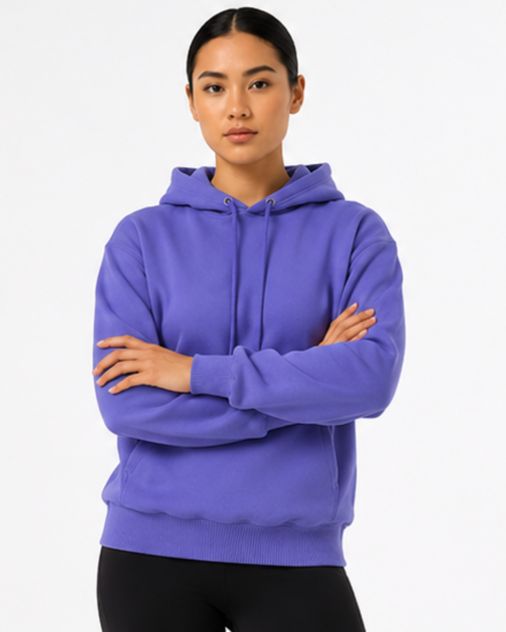 A woman modeling a purple pullover hoodie with a drawstring hood and kangaroo pocket, paired with black leggings, against a plain white studio background.